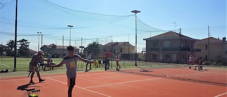 A tennis court with a net, players, and tennis balls.
