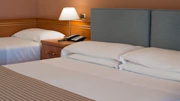 Una habitación de hotel con dos camas, una mesita de noche con lámpara y un teléfono.