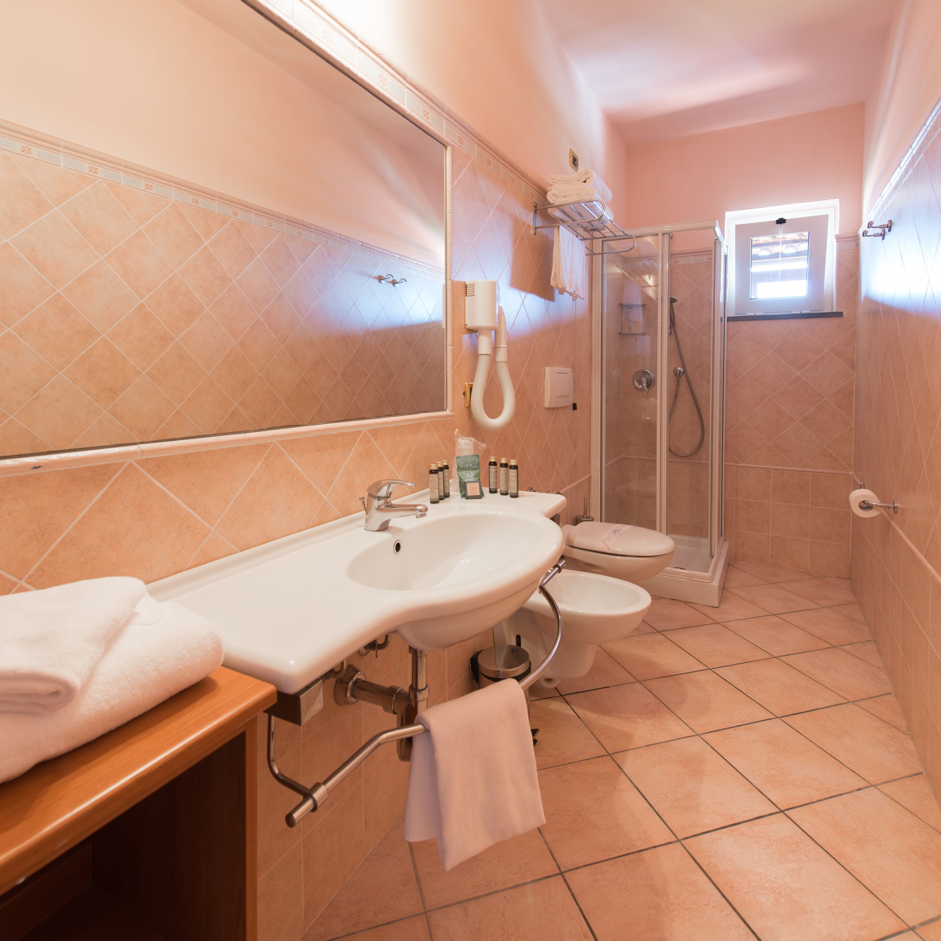A bathroom with a double sink, toilet, and a glass-enclosed shower.