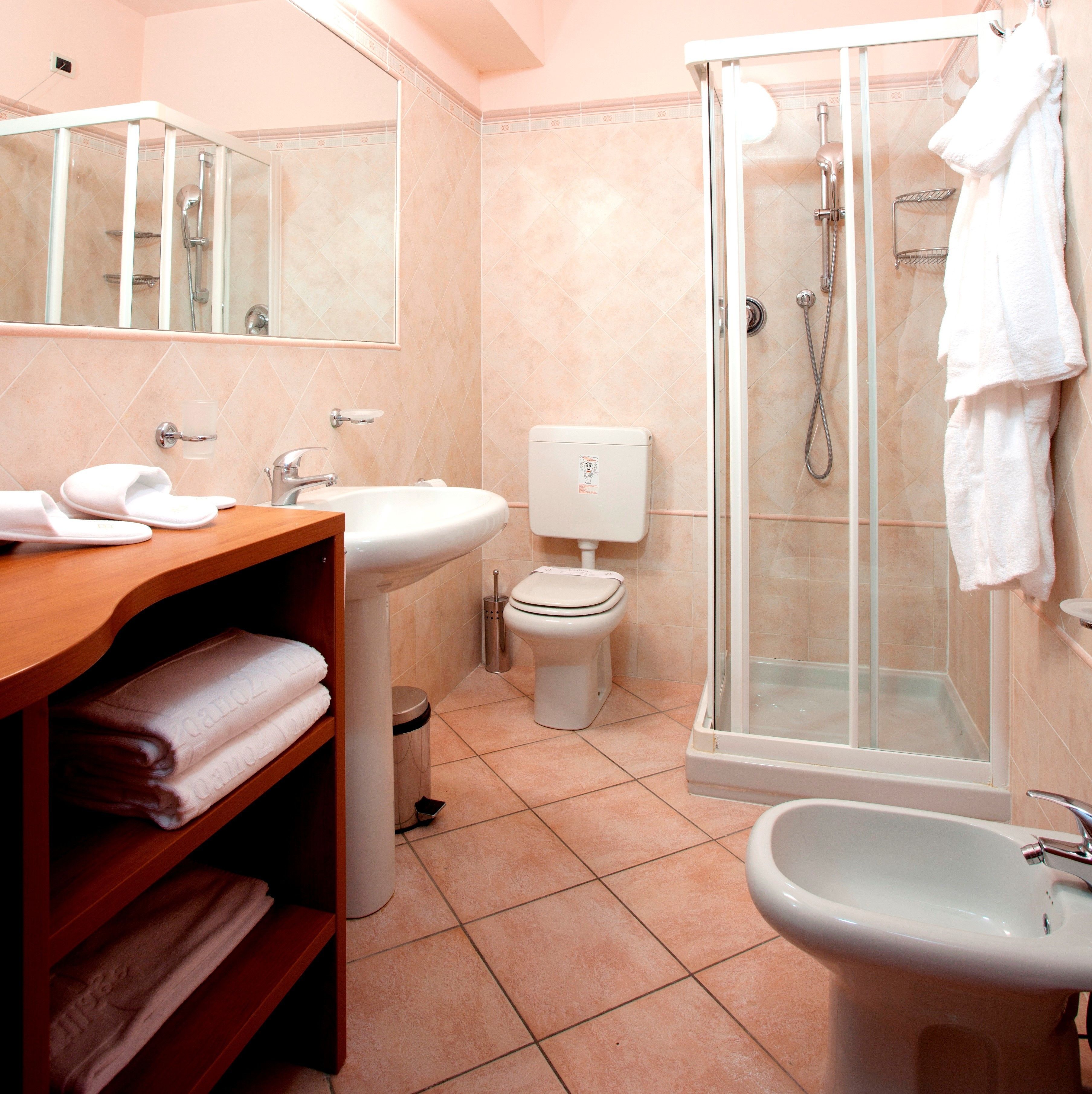 A modern bathroom with a shower, toilet, sink, and bidet.
