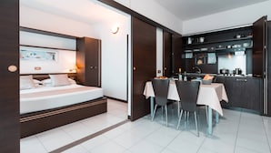 Una habitación de hotel moderna con una cama, mesita de noche y un pequeño comedor con sillas y una mesa.