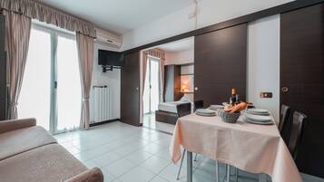 Une chambre d’hôtel moderne dotée d’un coin repas, d’un canapé et d’une télévision.
