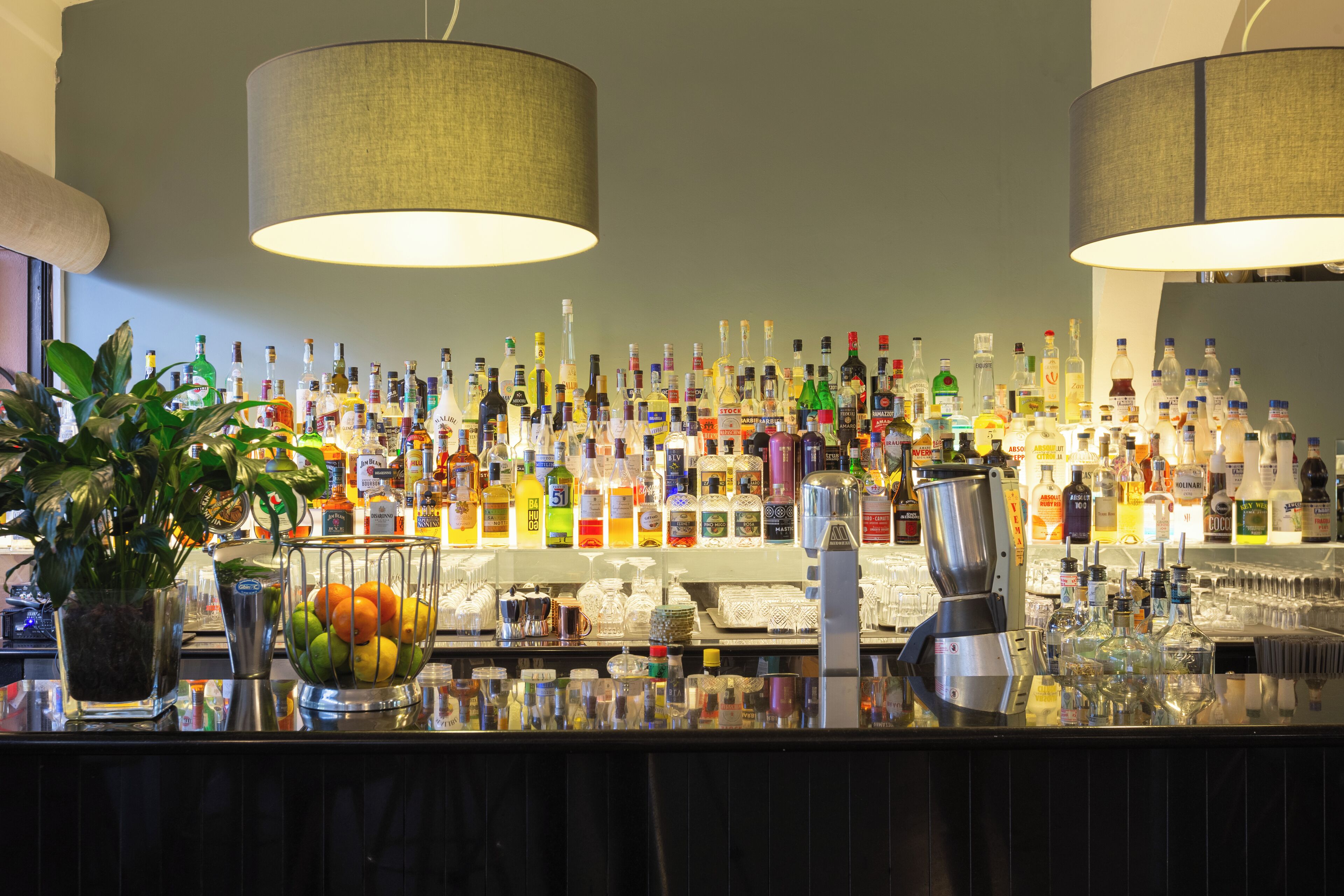 A bar with a variety of liquor bottles and a fruit bowl.