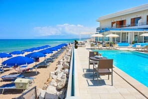 Una piscina al aire libre, sombrillas, sillones reclinables de piscina