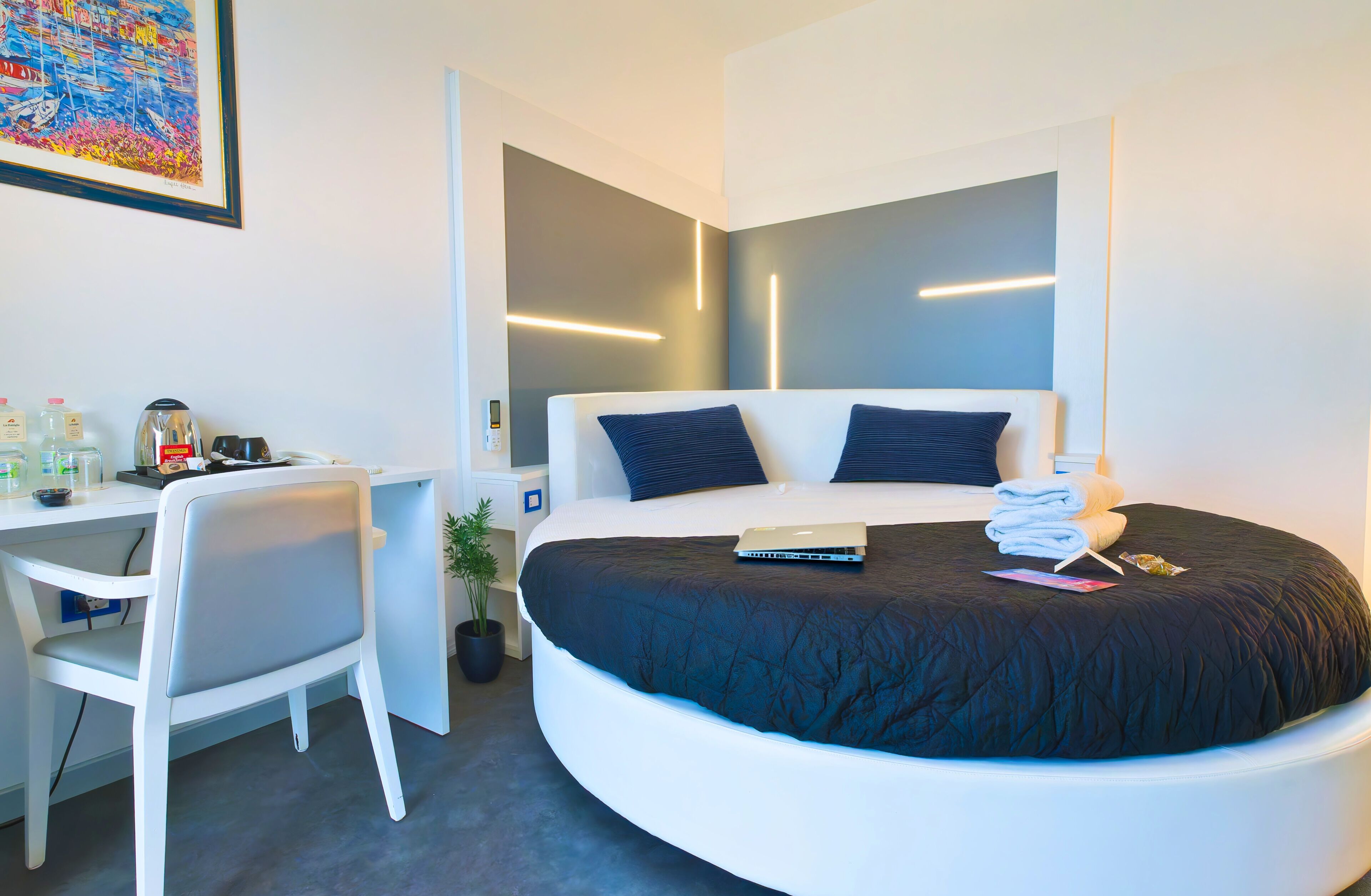A modern hotel room with a curved bed, a desk, and a chair.