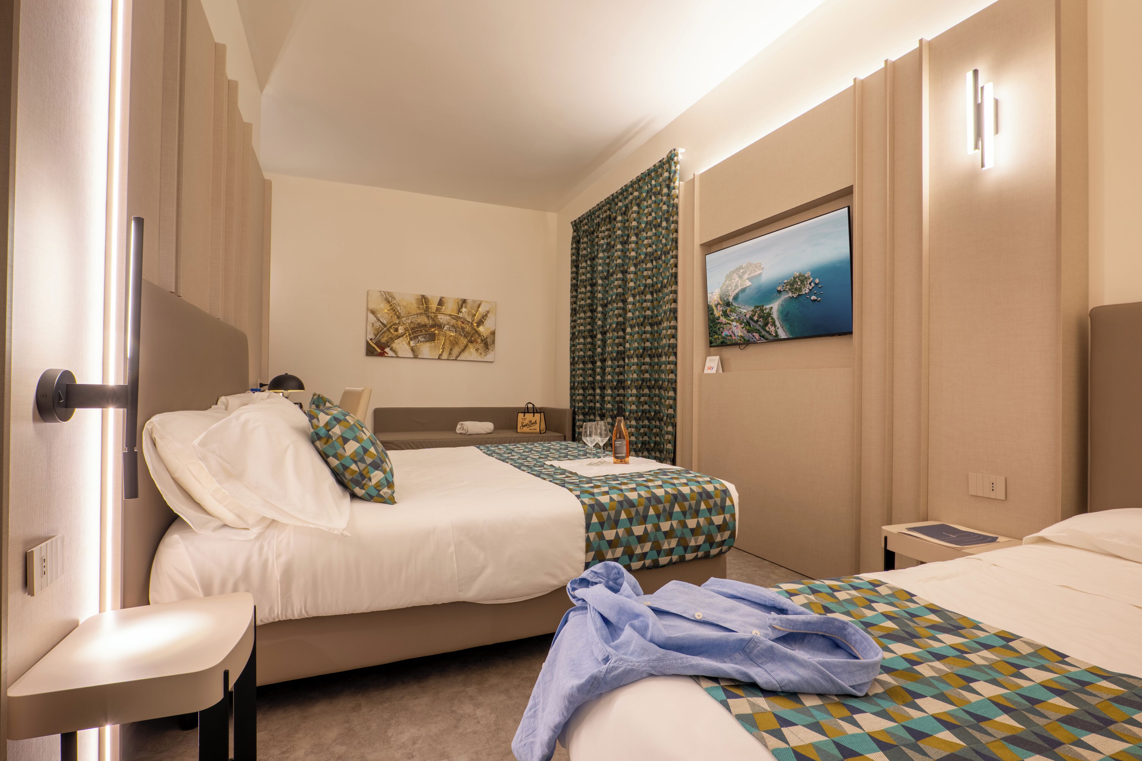 Habitación de hotel con dos camas, un televisor, un cuadro y una ventana.