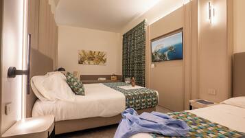 Habitación de hotel con dos camas, un televisor, un cuadro y una ventana.