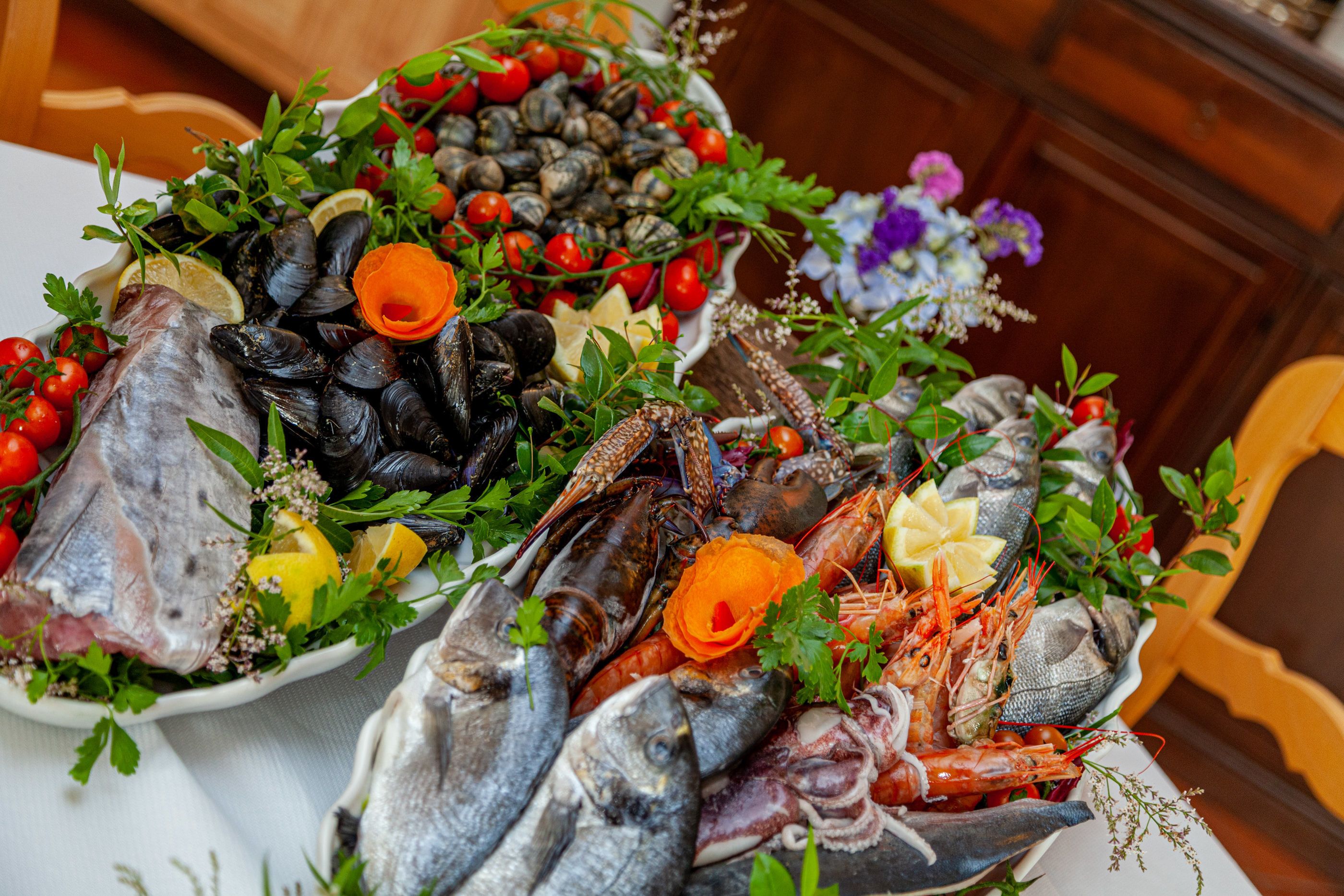A seafood platter with various types of fish, mussels, and shrimp, garnished with herbs and lemon slices.