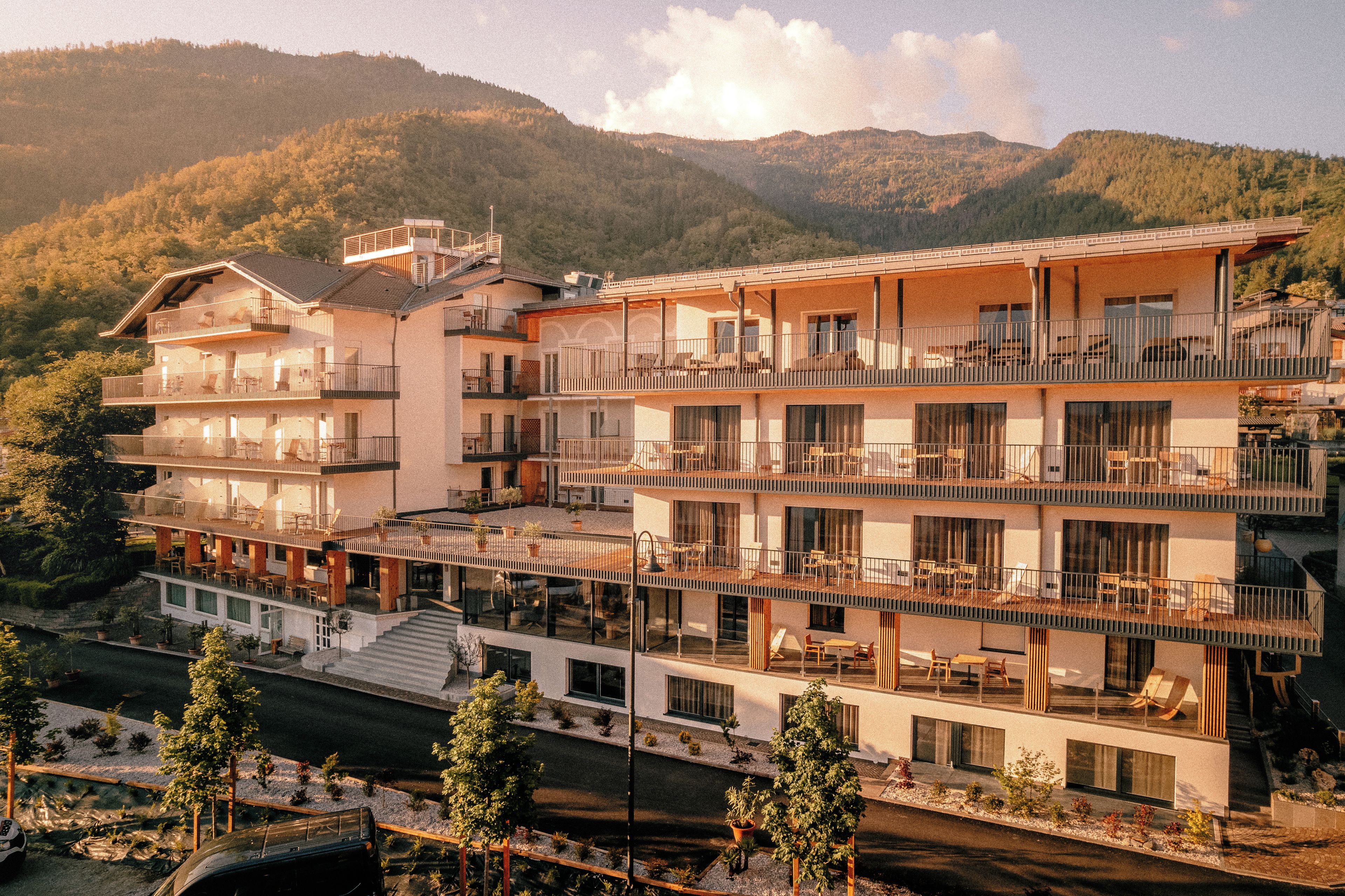Un hotel de varios pisos con balcones, una zona de piscina y vistas de las montañas circundantes.