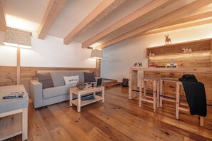 A cozy living room with a sofa, coffee table, and a wooden dining area. - Cristallo Levico Terme (Levico Terme)