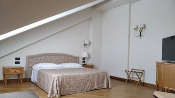 A bedroom with a bed, bedside tables, a TV, and a desk.