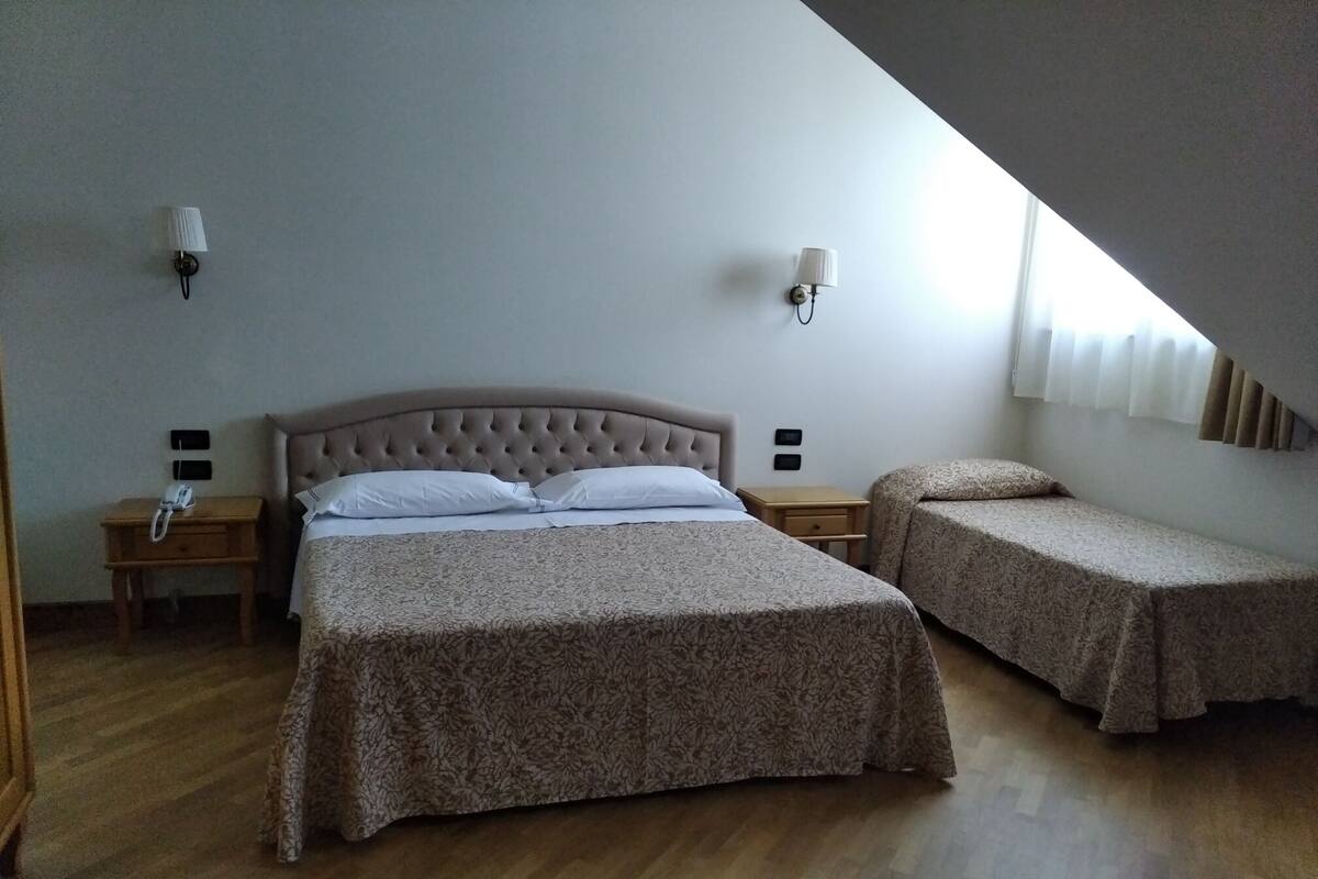 A bedroom with a large bed, two bedside tables, and a smaller bed.