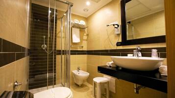 Un baño moderno con ducha de vidrio, un bidé, un lavamanos y un inodoro.