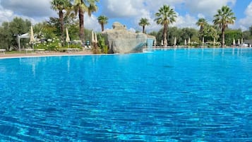 Una piscina al aire libre de temporada, sombrillas