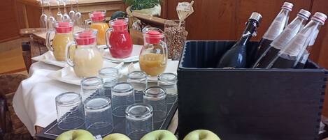 Una mesa con diferentes bebidas, incluyendo botellas y vasos, y varias manzanas.