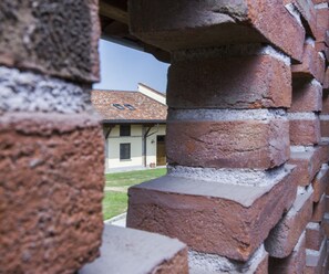A brick structure with a view of a building with a tiled roof and a door. - Country Hotel Castelbarco (Vaprio d'Adda)