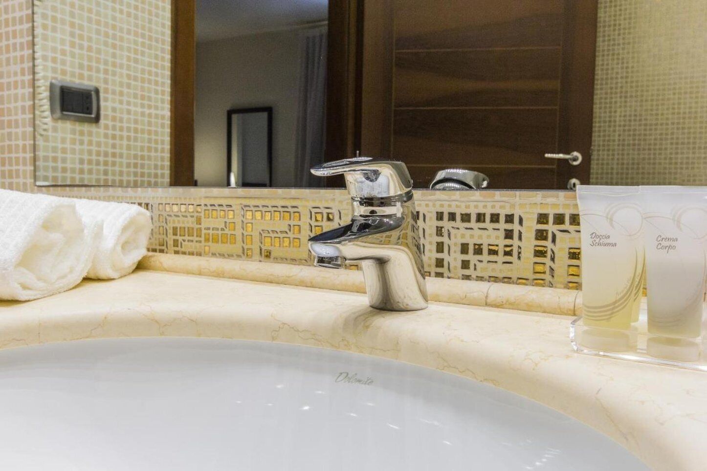 A bathroom sink with a chrome faucet, a towel, and two bottles of lotion.