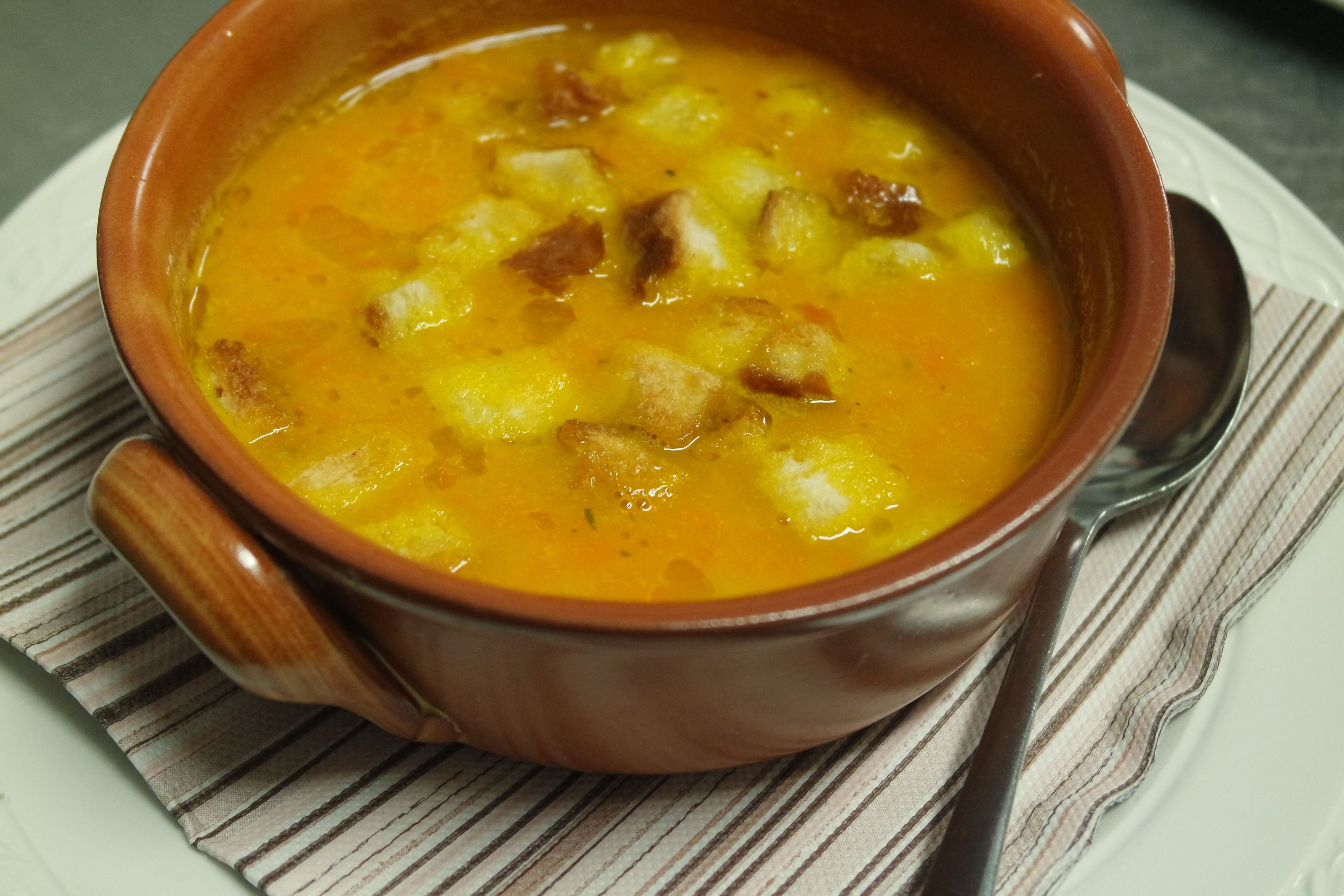 A bowl of soup with croutons on a striped napkin.