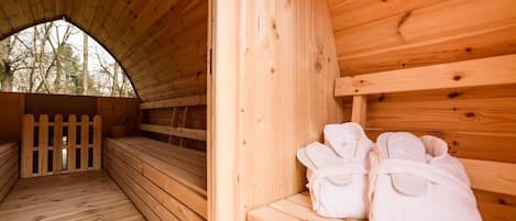 Uma sauna de madeira com bancos e um banco com toalhas.
