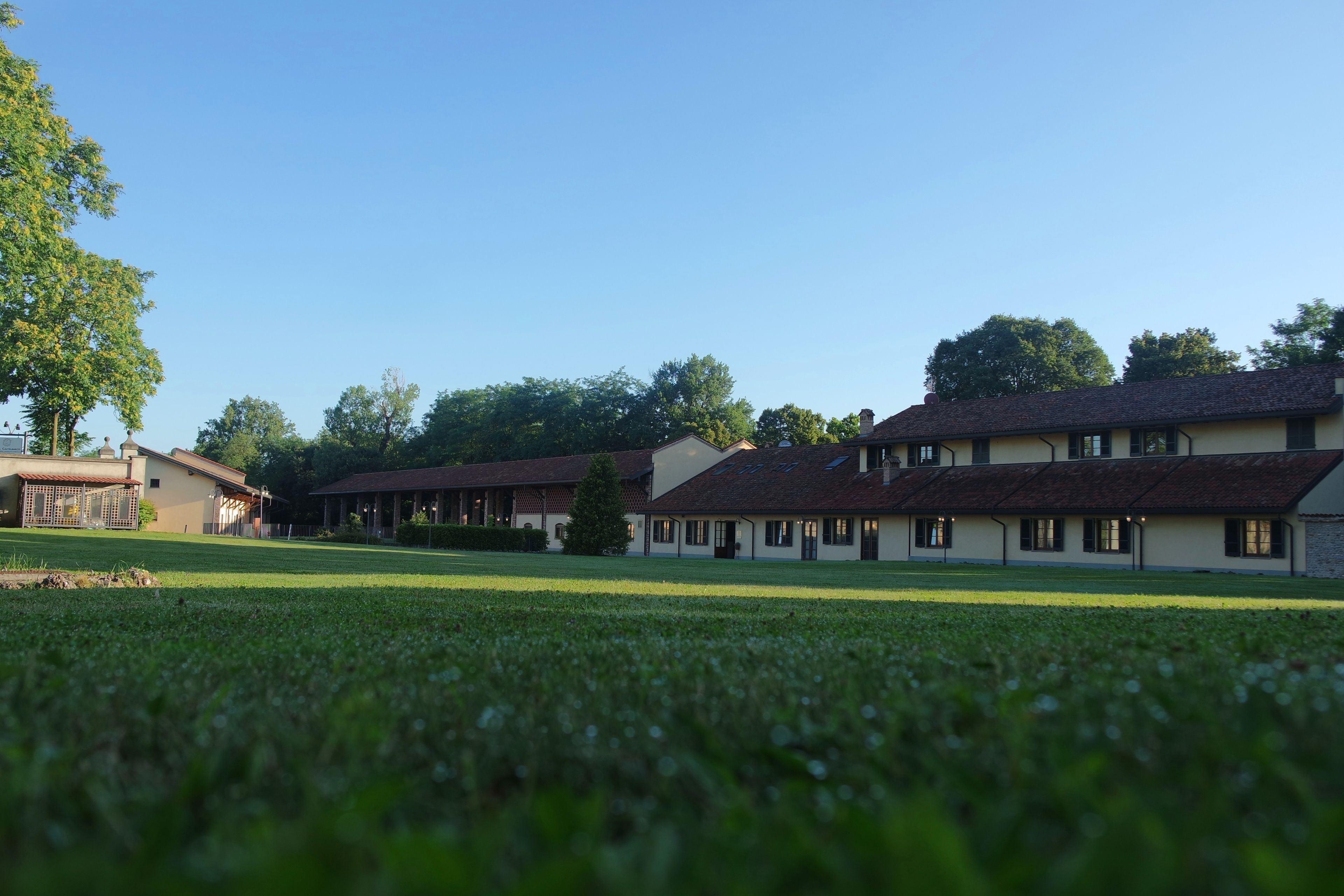 A building with multiple rooms, a lawn, and trees in the background.