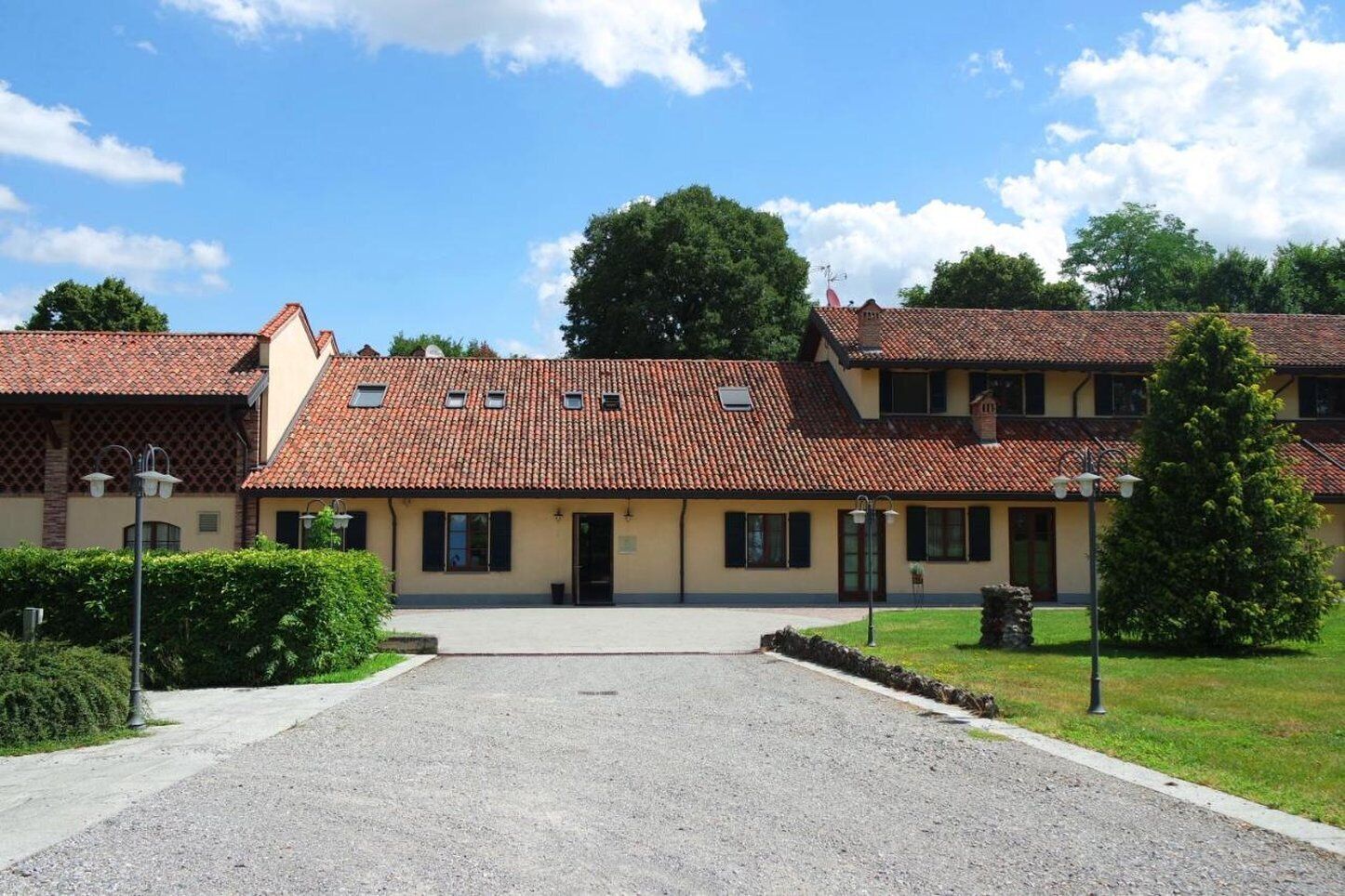 A two-story building with a tiled roof, a gravel driveway, and a well-maintained lawn.