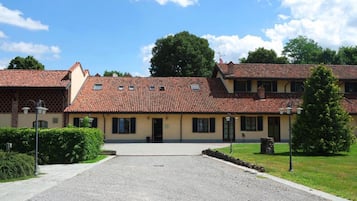 A two-story building with a tiled roof, a gravel driveway, and a well-maintained lawn.