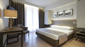 A modern hotel room with a bed, a desk, a chair, and a TV. - Park Hotel Chianti (Barberino Tavarnelle)
