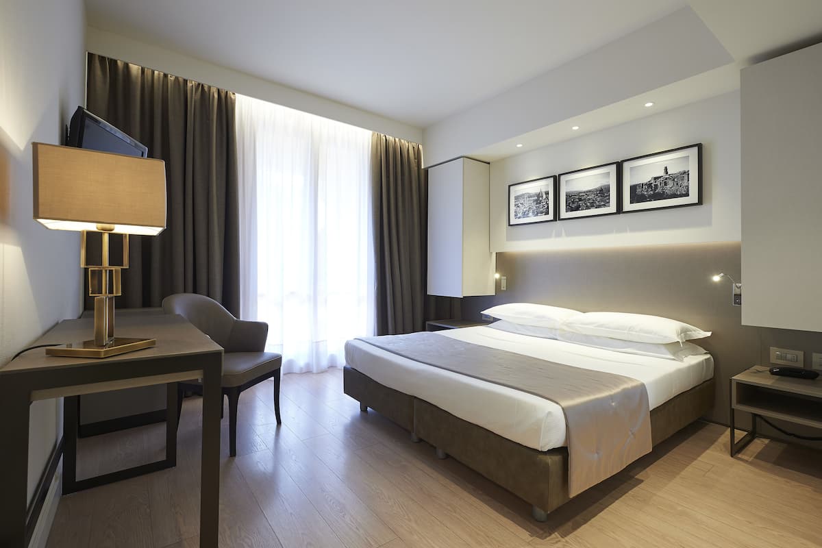 Een moderne hotelkamer met een bed, bureau, stoel en televisie.