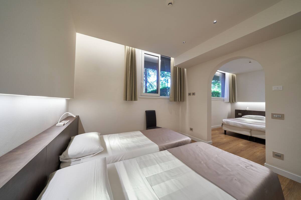 Een moderne hotelkamer met twee bedden, een bureau en een raam met gordijnen.