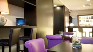 A modern bar area with purple seating, a laptop on a shelf, and a wine display. - Park Hotel Chianti (Barberino Tavarnelle)
