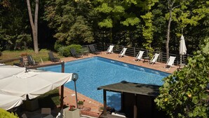 A rectangular swimming pool with lounge chairs and umbrellas, surrounded by trees and greenery. - Park Hotel Chianti (Barberino Tavarnelle)