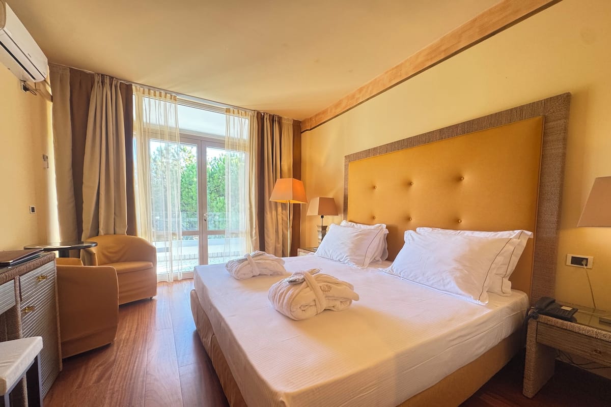 Una habitación de hotel con una cama grande, una silla, un escritorio y una lámpara.