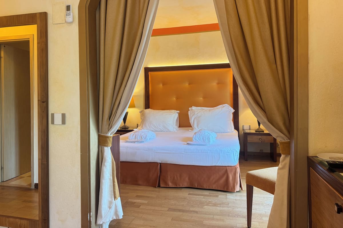 Una habitación de hotel con cama, cortinas, mesilla de noche y mesita de noche.