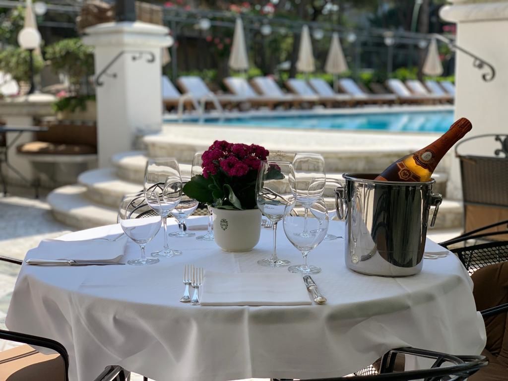 A table set for a meal with a bottle of champagne, a flower vase, and wine glasses.