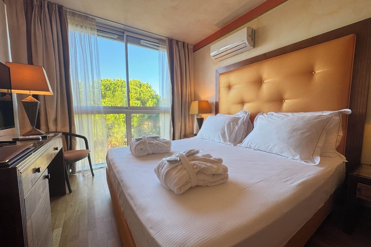 Una habitación de hotel con una cama grande, un escritorio, una silla y una ventana con cortinas.
