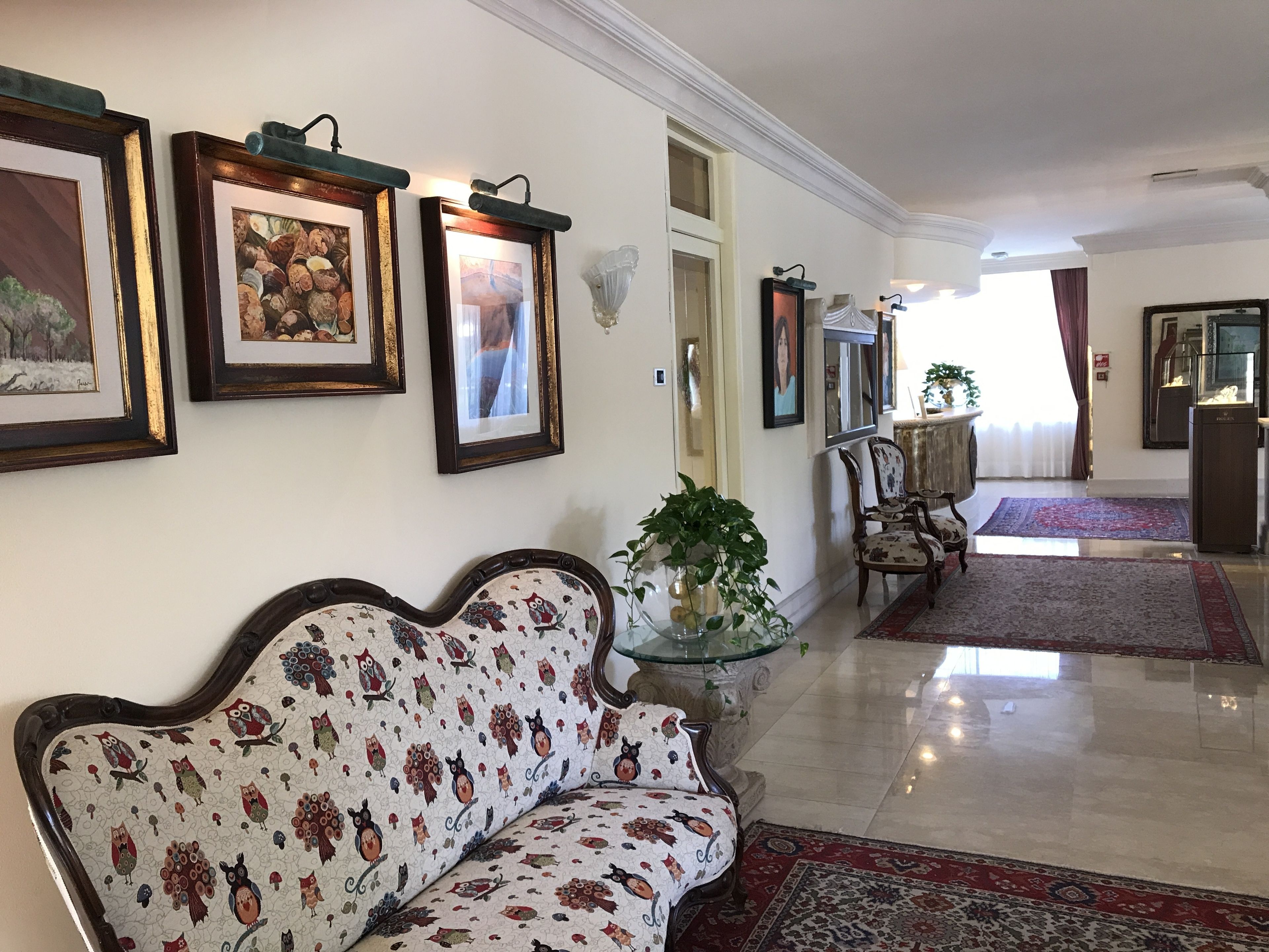 A hallway with a sofa, framed artwork, a mirror, and a patterned rug.