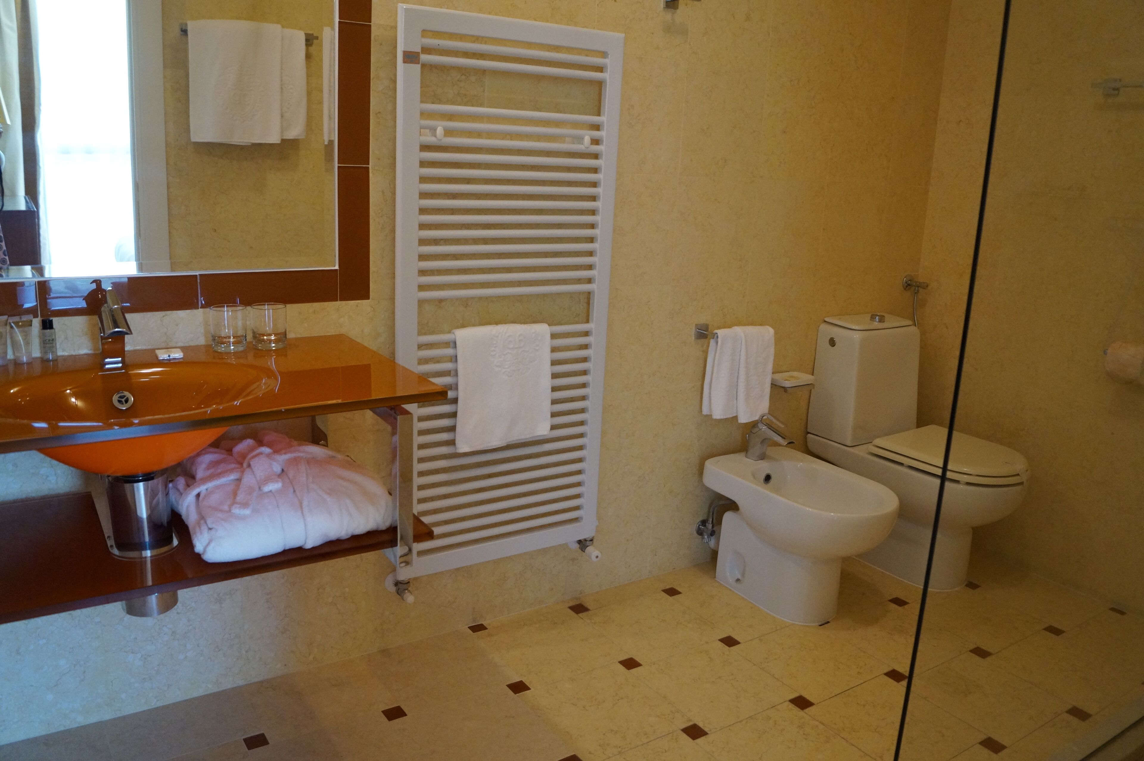 Ein Badezimmer mit Waschbecken, Handtuchhalter, Toilette, Bidet und Spiegel.