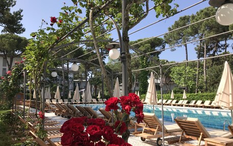 A poolside area with lounge chairs, umbrellas, and a pergola with climbing plants.