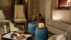 Una sala de estar acogedora con chimenea, asientos cómodos y una mesita con velas y aperitivos.