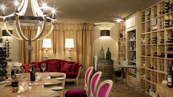 A dining area with a chandelier, red sofa, wooden dining table, and wine racks.