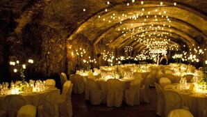 Un salón de banquetes interior con mesas redondas dispuestas para comer, decorado con velas y flores.