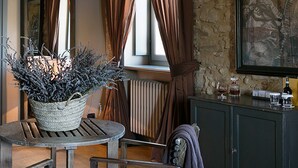 Una habitación acogedora con cama, una mesa con planta, un radiador y un armario con botellas.
