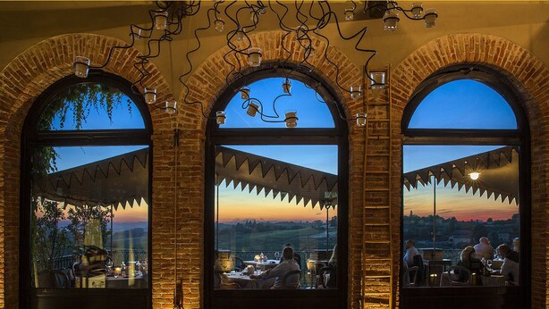 Un restaurante con tres ventanales arqueados que dan a un paisaje pintoresco.