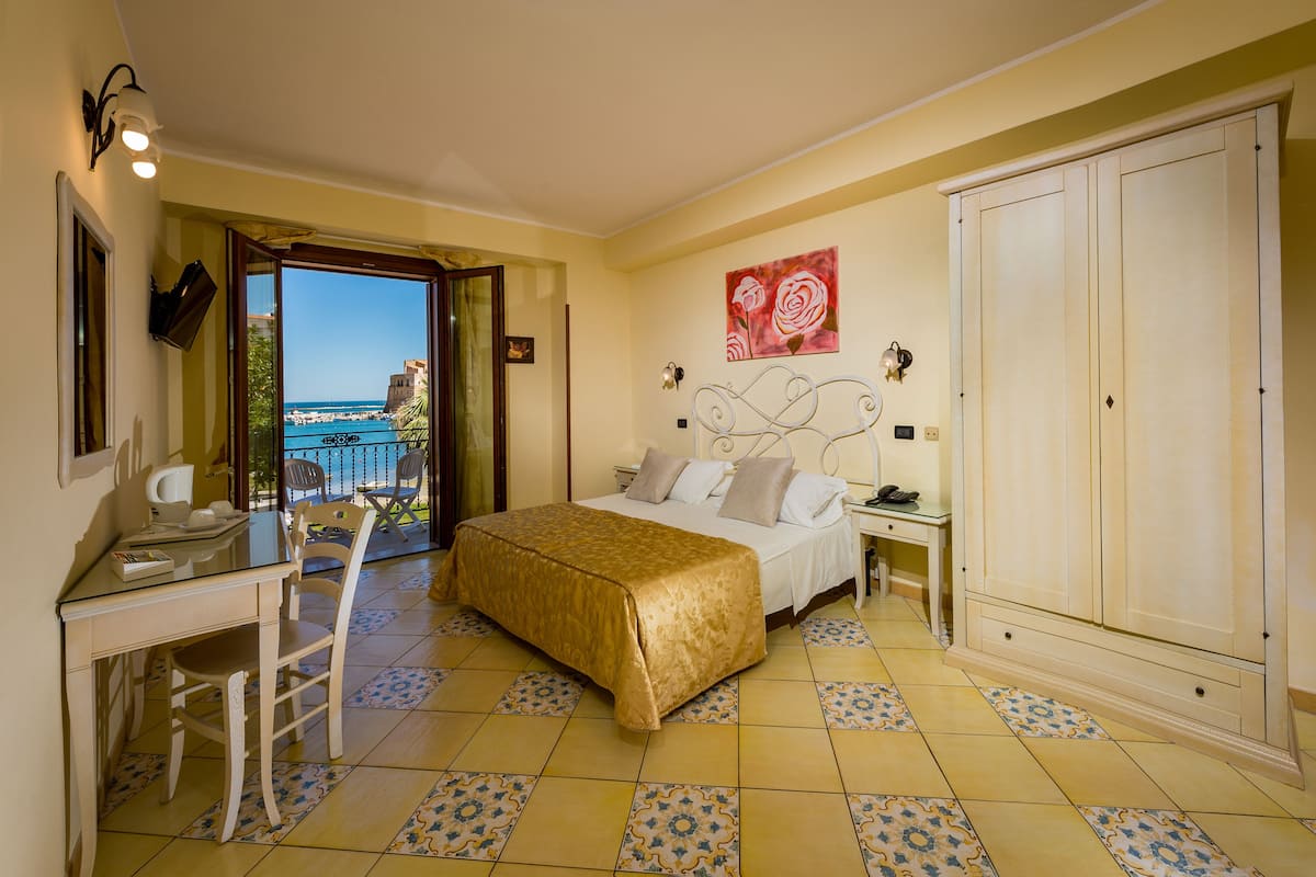 Ein Schlafzimmer mit Bett, Schreibtisch und Meerblick.