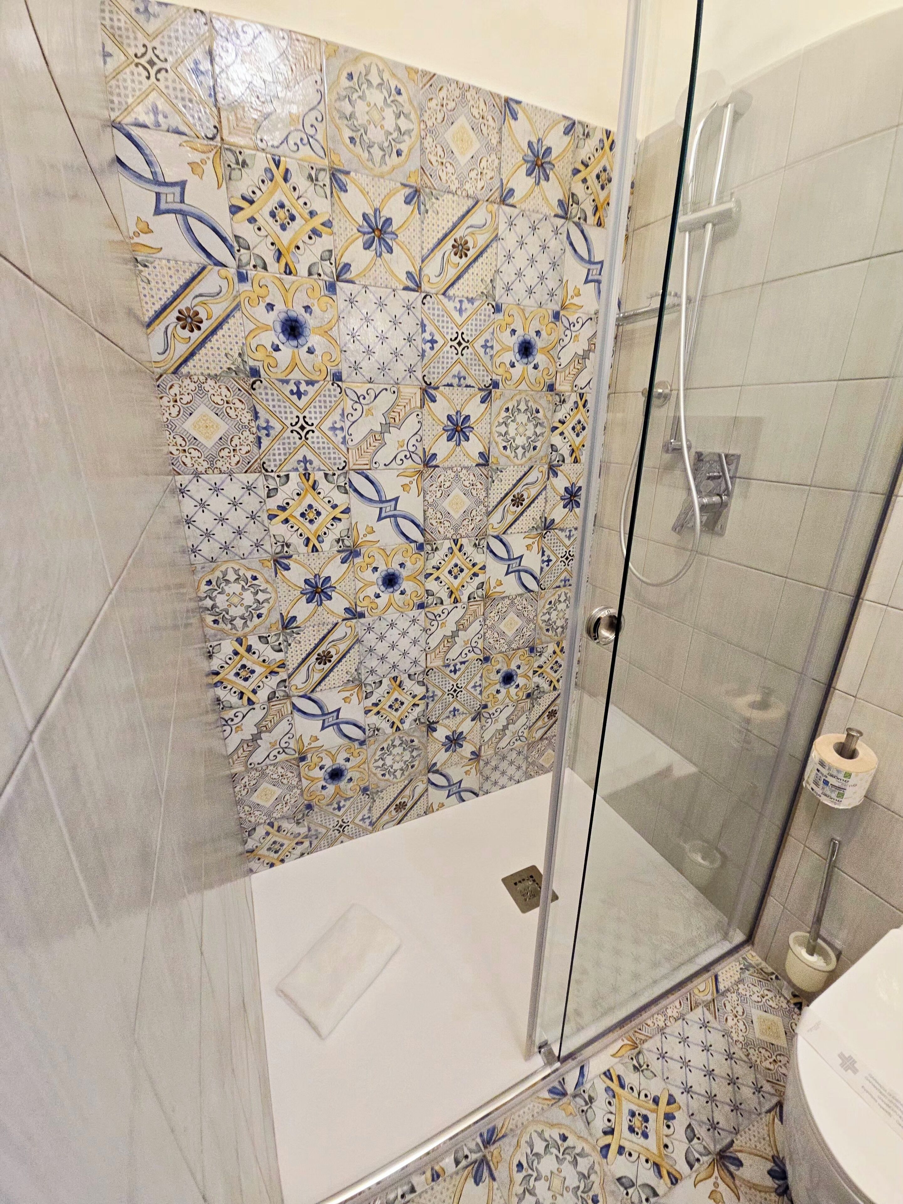 A bathroom with a shower area, tiled walls, and a toilet.
