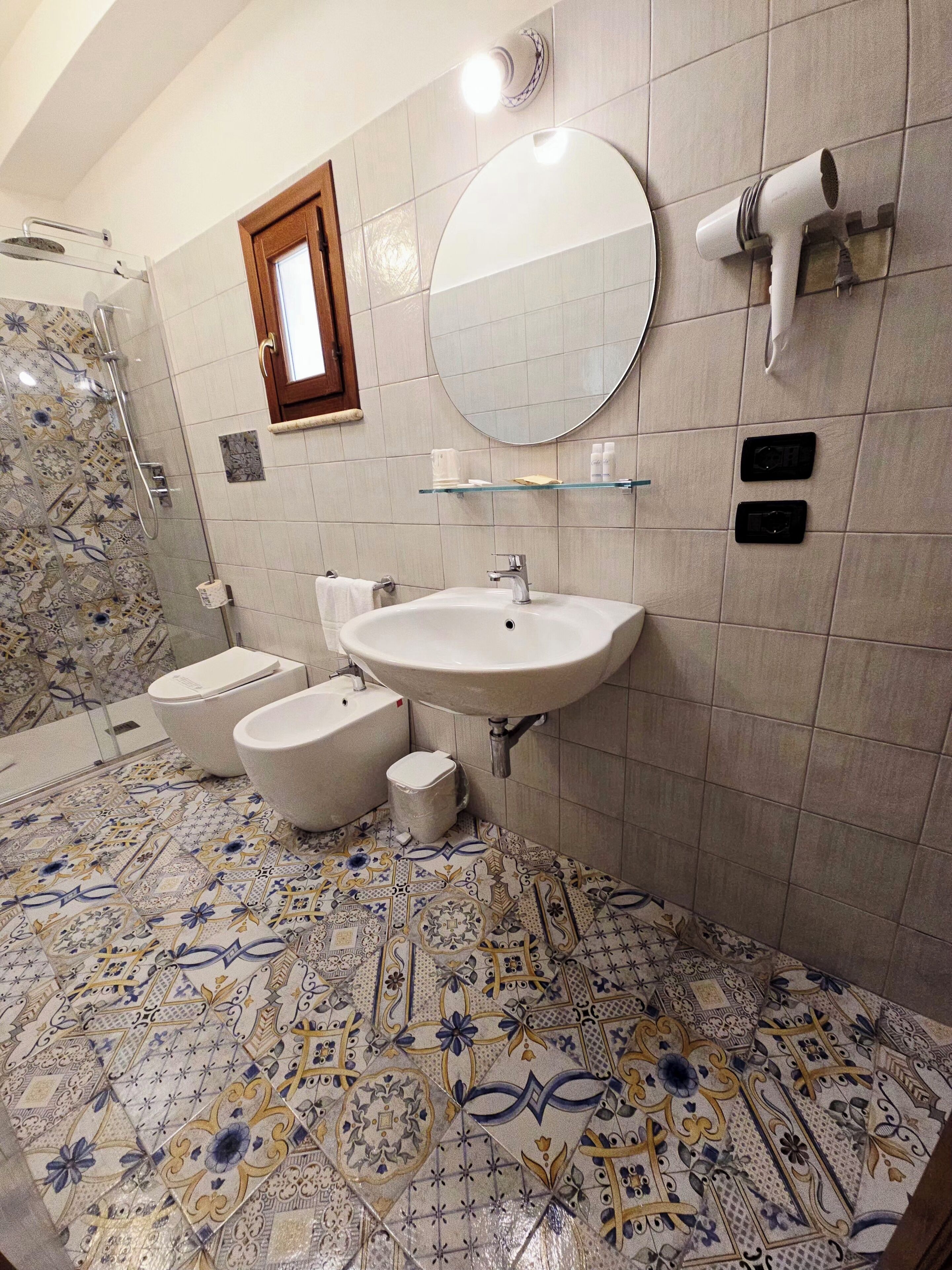 Ein Badezimmer mit Toilette, Bidet, Waschbecken, Spiegel und Handtuchhalter.