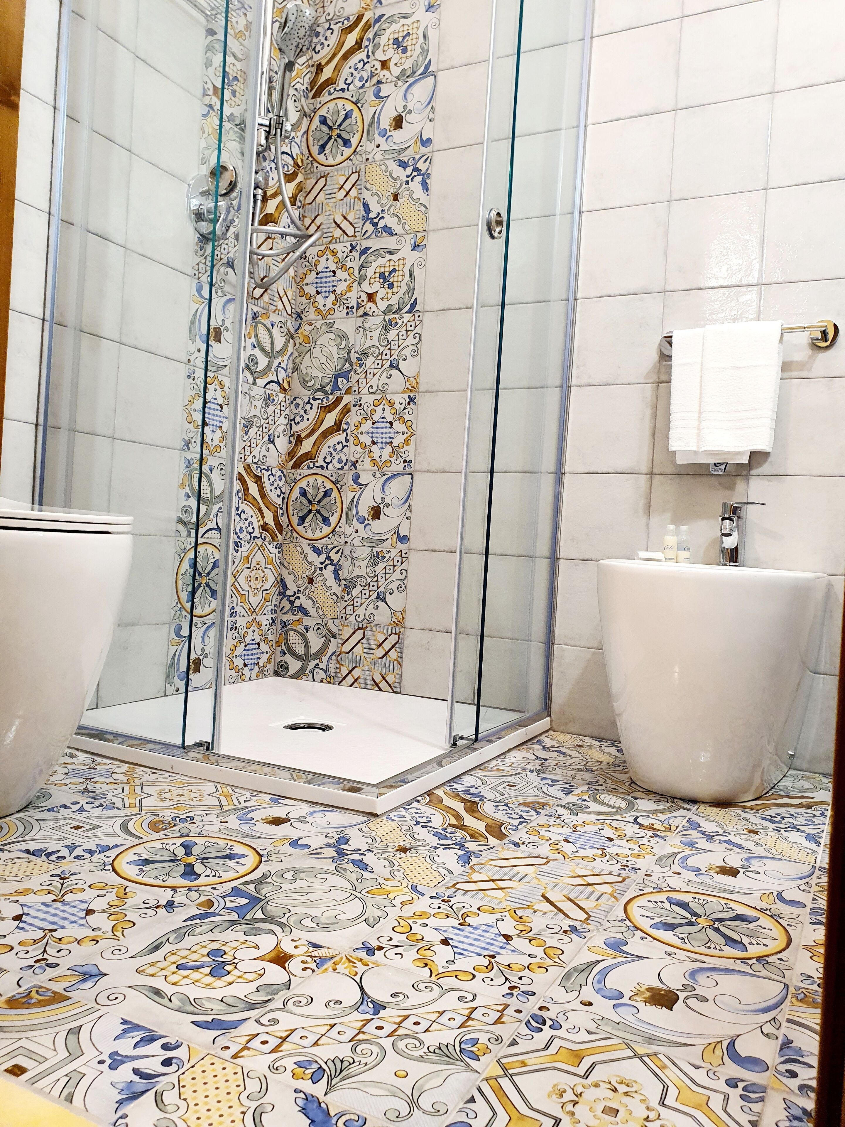 Un baño con ducha, dos lavamanos y baldosas de suelo estampadas.