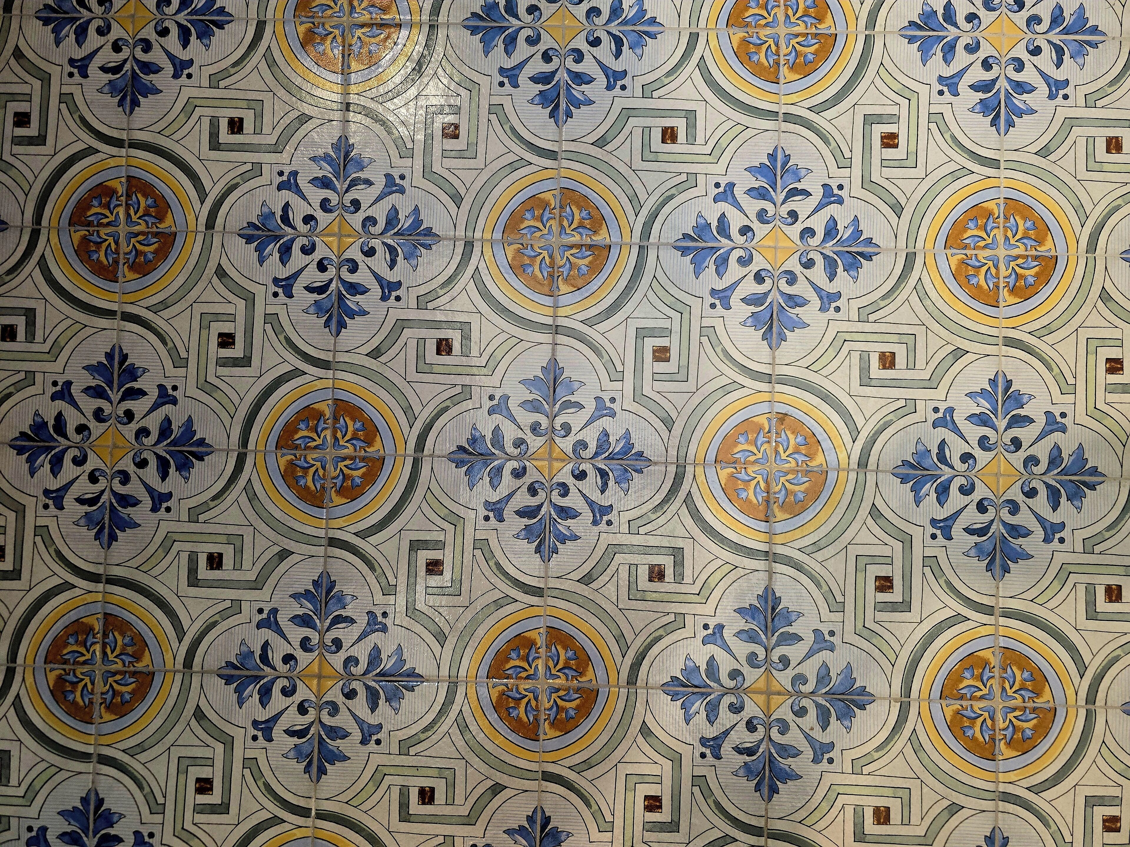 A tiled wall with a repeating geometric pattern featuring blue and gold accents.