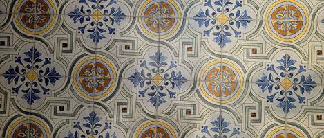 A tiled wall with a repeating geometric pattern featuring blue and gold accents.