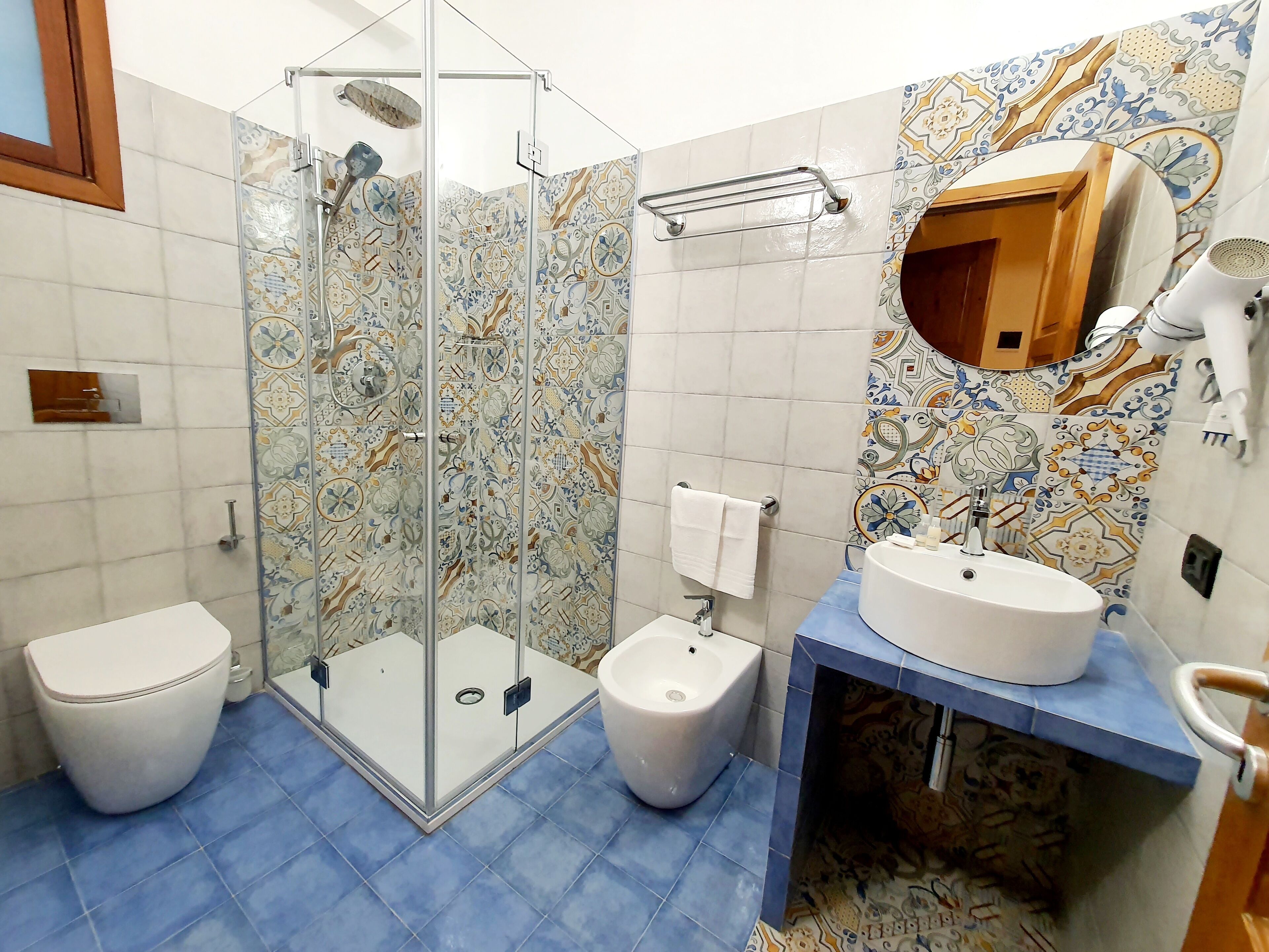 A bathroom with a glass-enclosed shower, a toilet, a bidet, and a sink with a mirror.